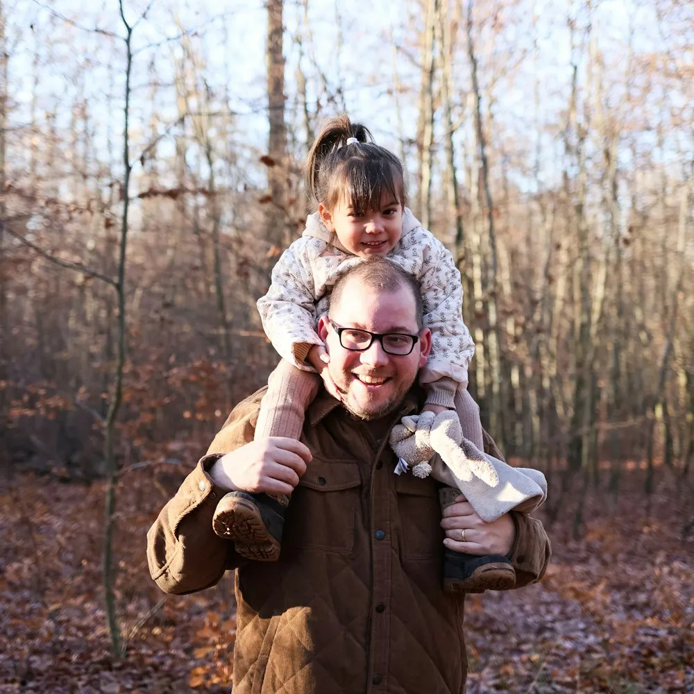 Padre caminando por el bosque con su hija en hombros